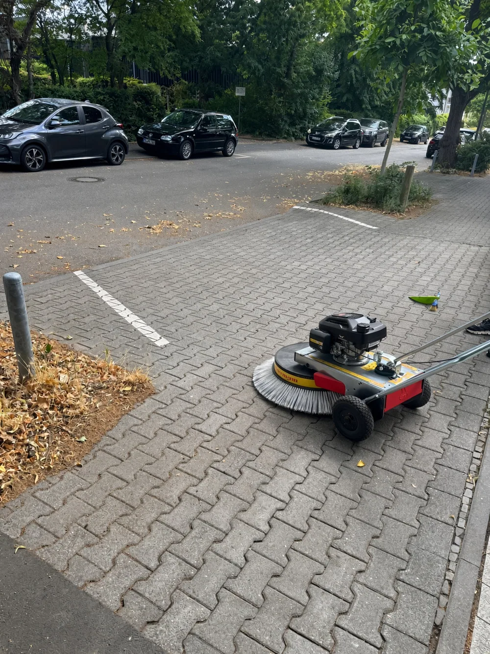 Nach dem Kehren: derselbe Gehweg ist gefegt; die verwendete Kehrmaschine bleibt sichtbar